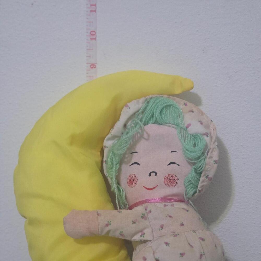 vintage dan brechner doll with green yarn hair and floral print on a yellow cres